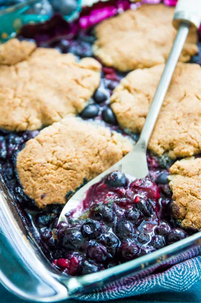 A pan of blueberry raspberry cobbler with a spoon in it