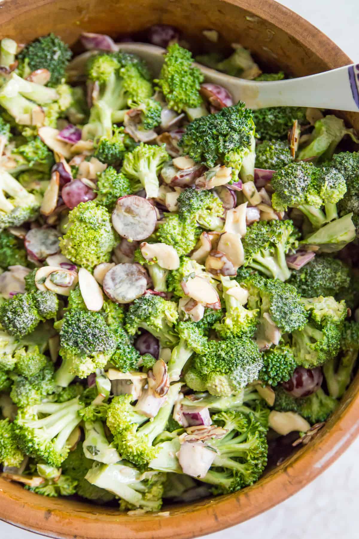 A large bowl of broccoli salad with a serving spoon in it.