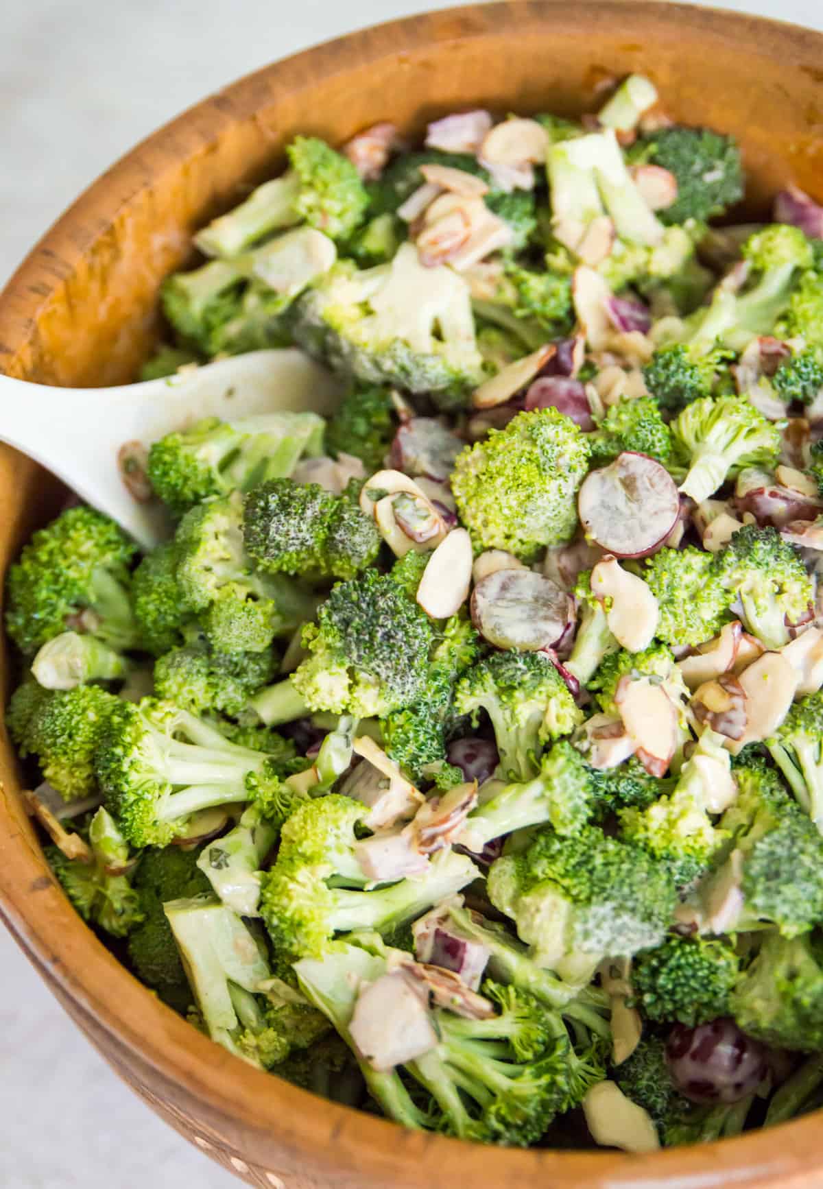 Broccoli salad in a large bowl being mixed with a large spoon.