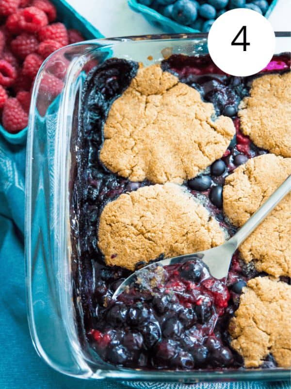 A glass baking dish with a blueberry raspberry cobbler in it.
