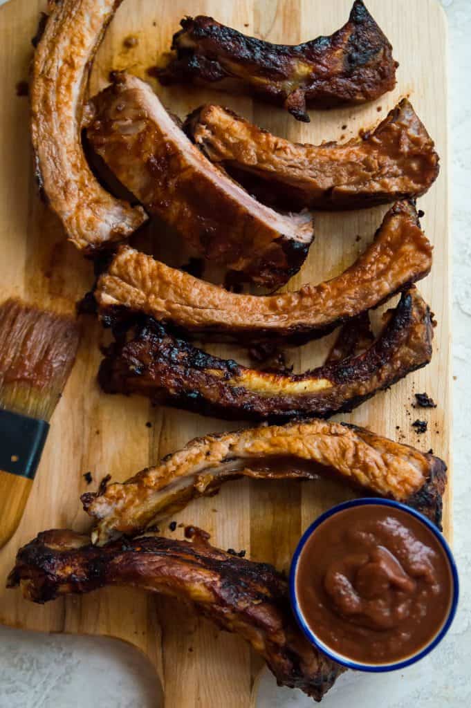 Air fryer ribs coated in bbq sauce on a wooden cutting board
