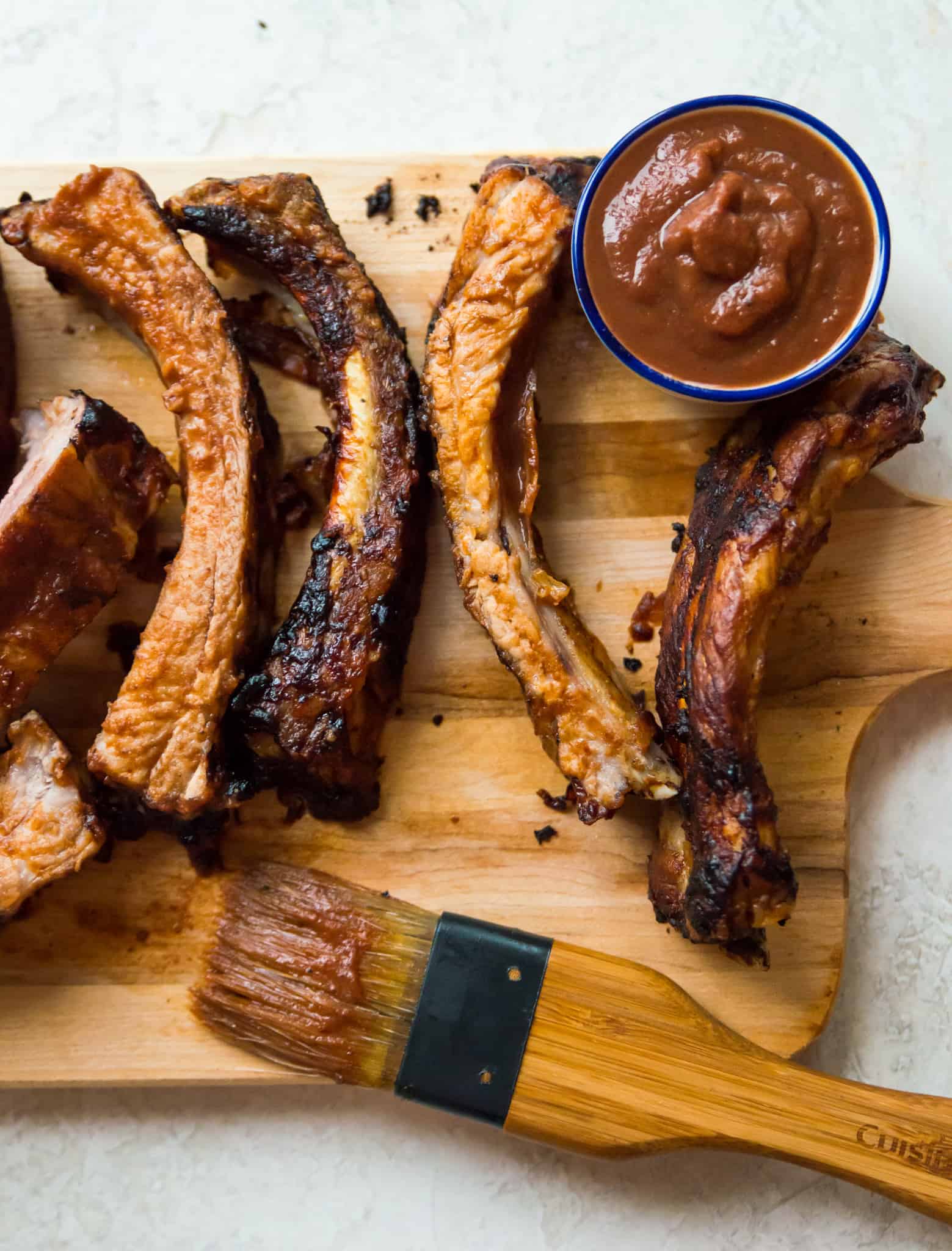 Cooked ribs coated in barbecue sauce on a serving board. 