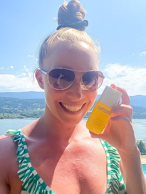 A girl in a bikini holding a bottle of the Beautycounter vitamin C serum