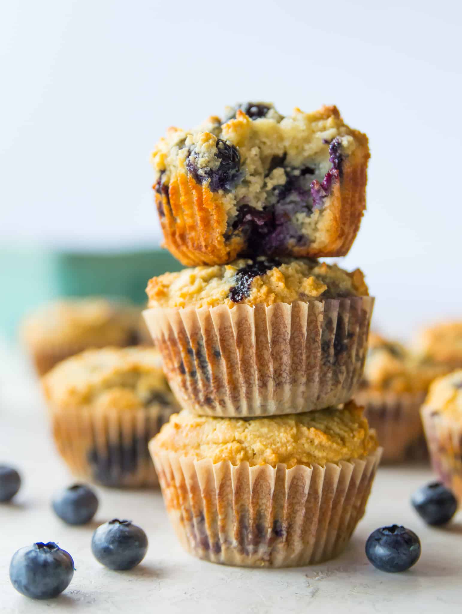 A stack of three lemon blueberry muffins, with a bite out of the top muffin.