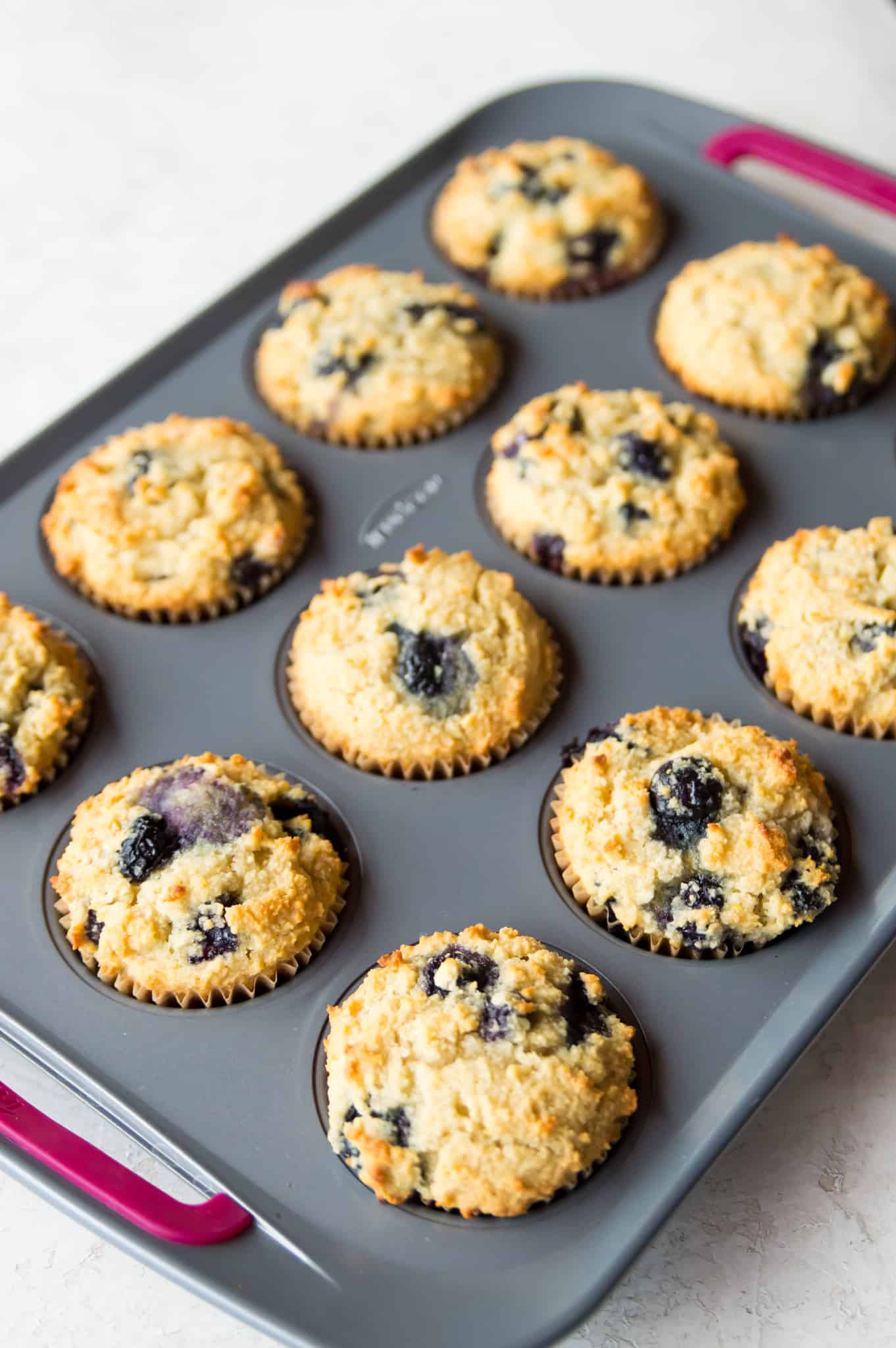 A muffin tray filled with cooked paleo lemon blueberry muffins.