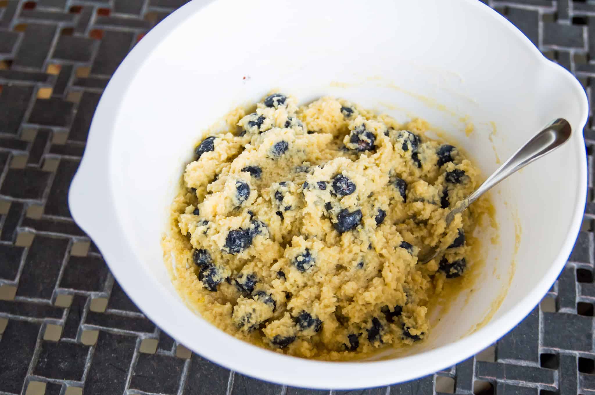 A mixing bowl with a blueberry muffin batter in it.