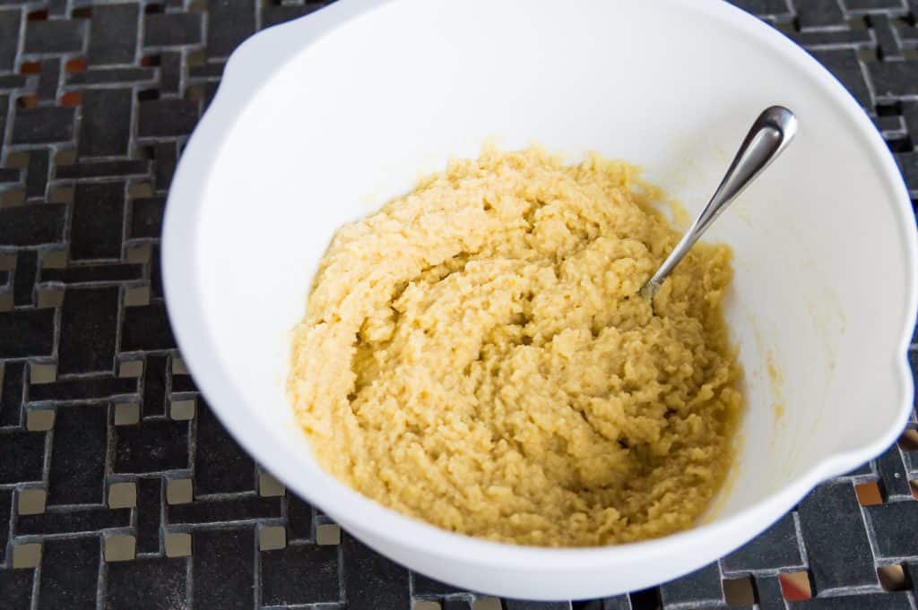 The dough for making lemon blueberry muffins in a large bowl with a spoon in it.