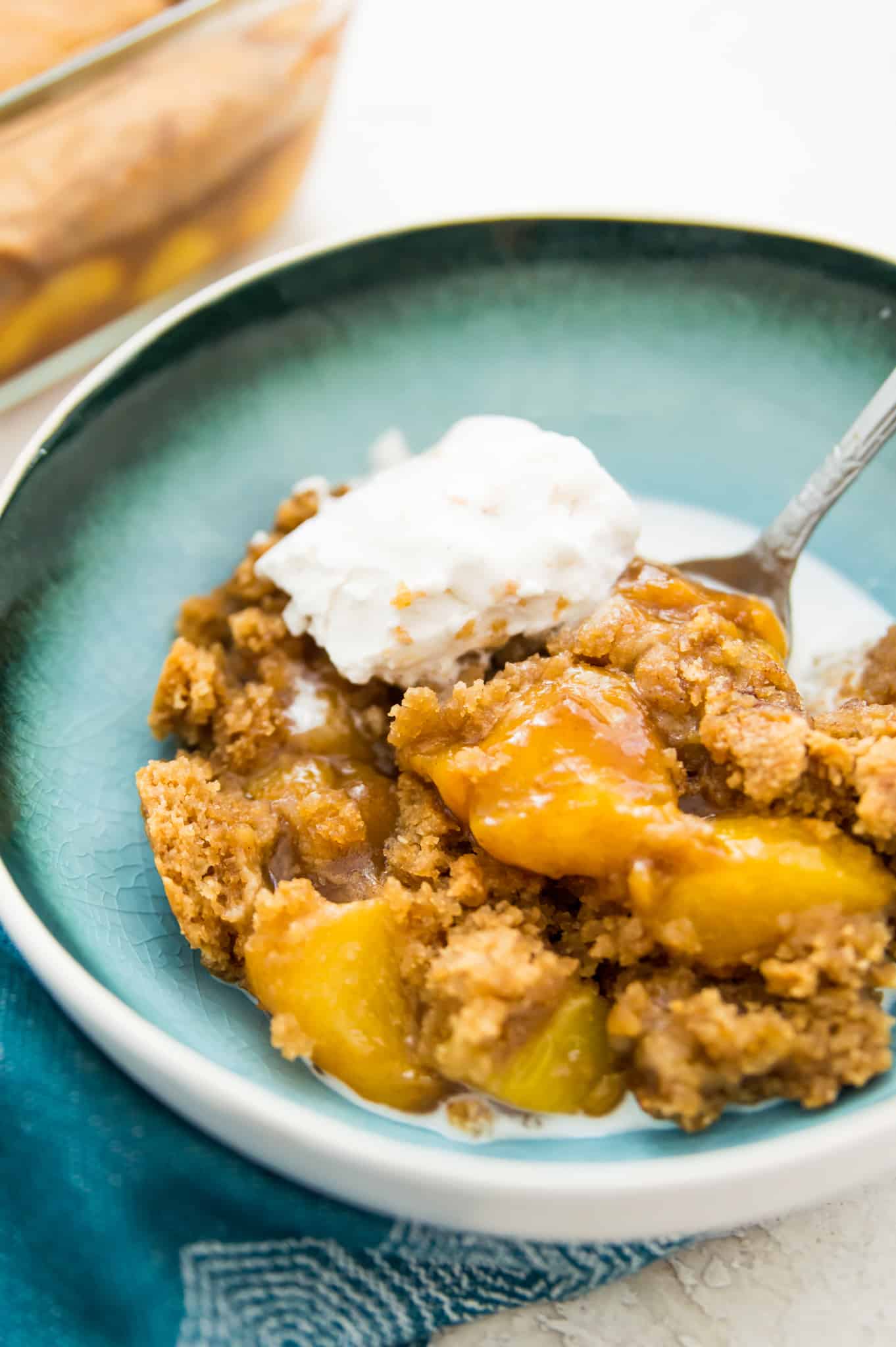A bowl of peach cobbler with vanilla ice cream on top.