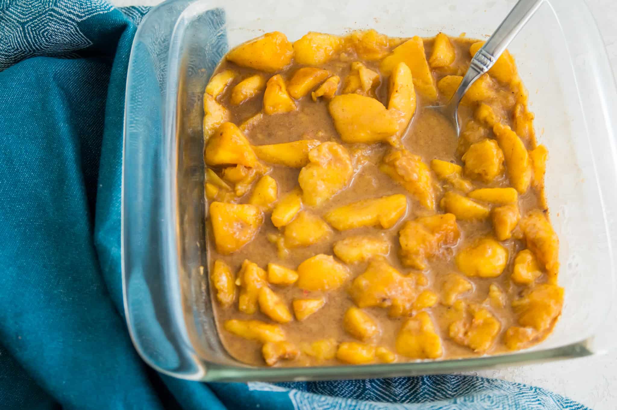 A glass baking dish with peaches and brown sugar in it.