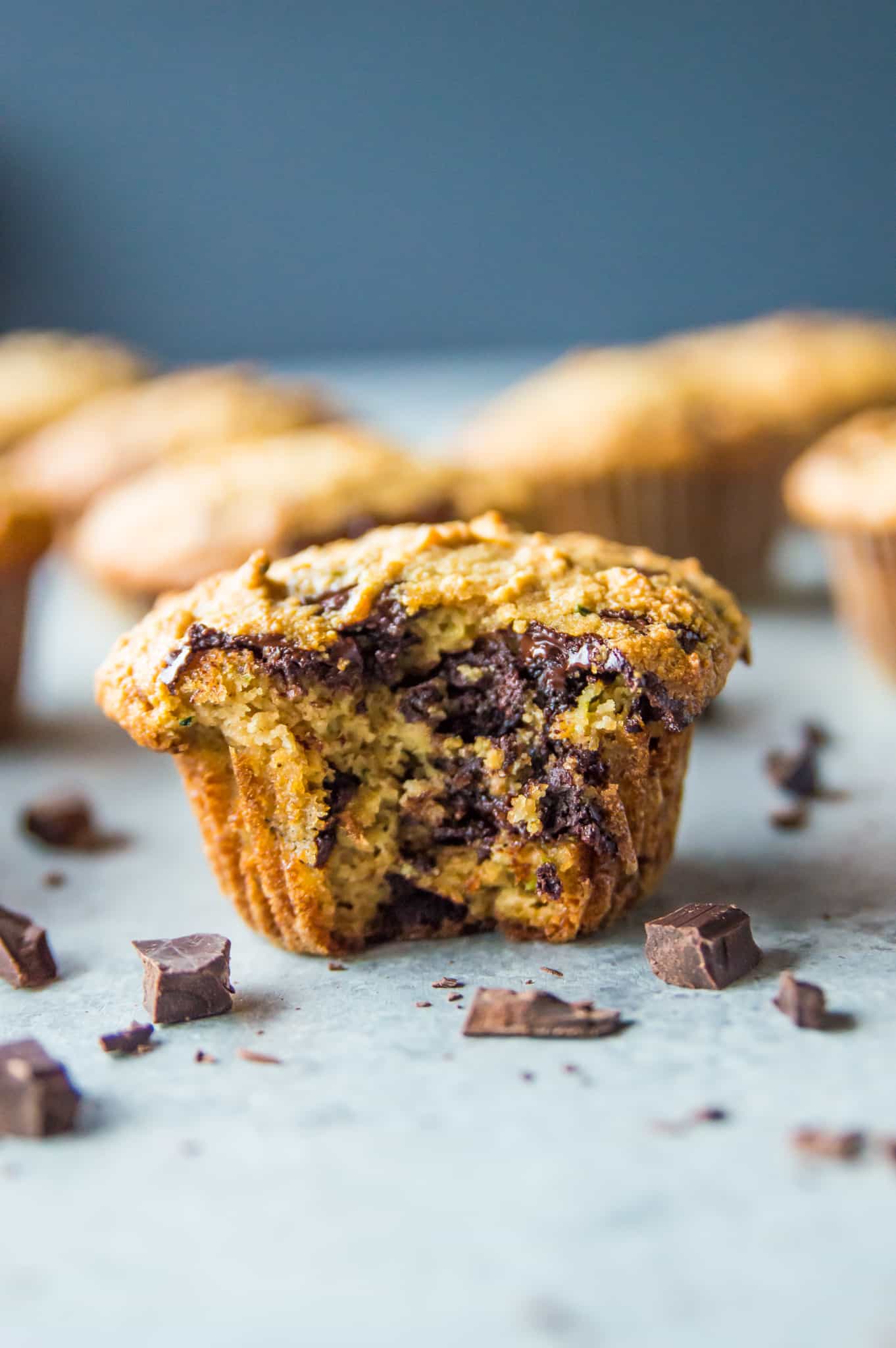 A paleo zucchini muffin with chunks of chocolate in it and a bite taken out of it.