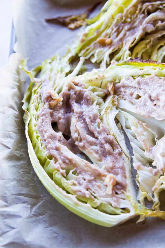 A tray of roasted cut cabbage with dressing on top and chopped walnuts