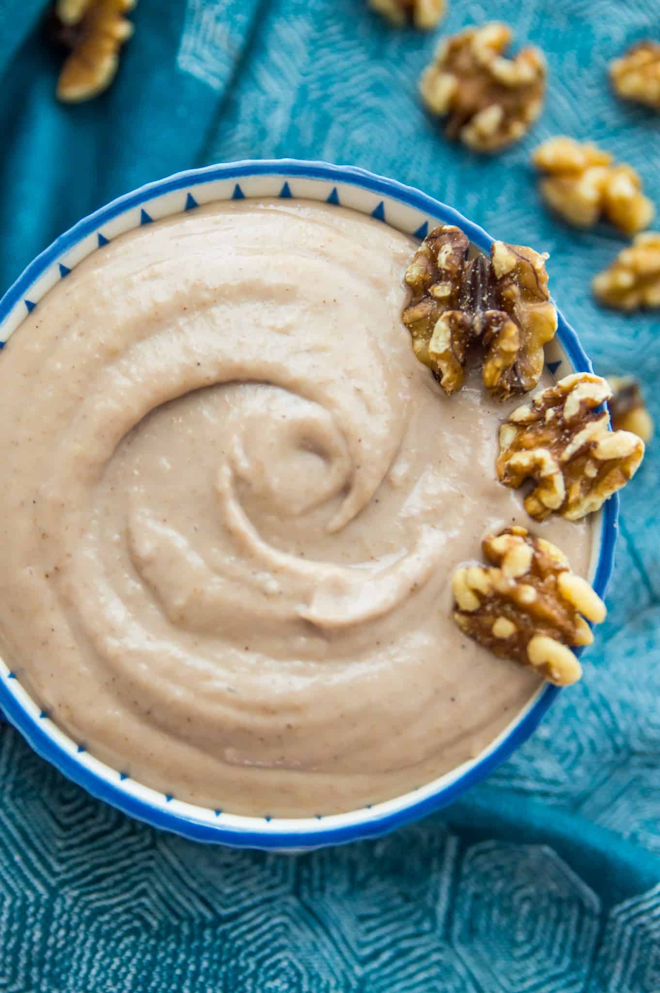 A bowl of walnut dressing with walnuts on top for garnish.