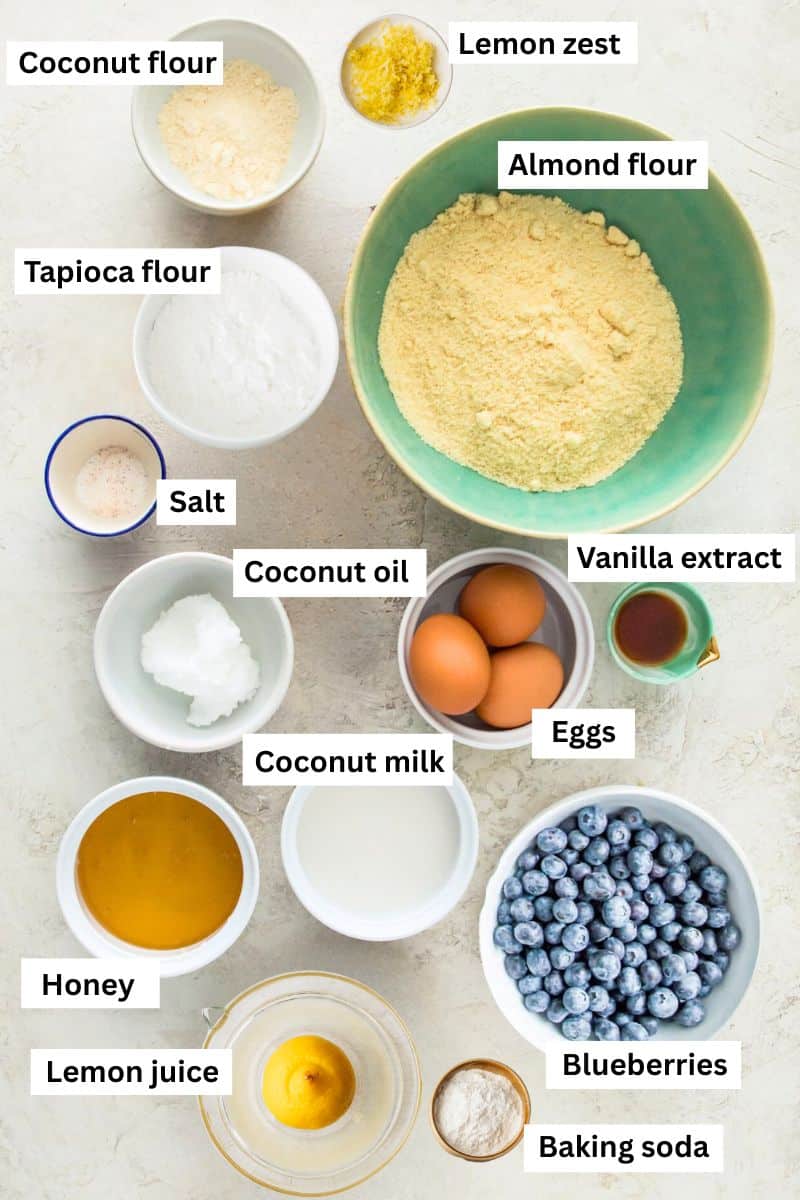 The ingredients needed to make lemon blueberry muffins separated into bowls including flour, eggs, honey, lemon zest, lemon juice and blueberries.