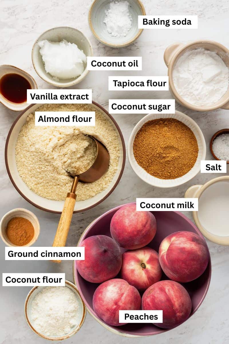 The ingredients needed to make a peach cobbler separated into bowls including peaches, flour, sugar, and ground cinnamon.