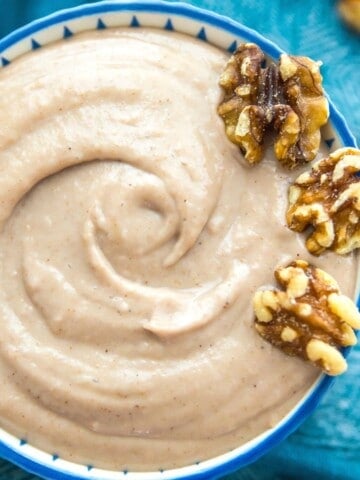 A bowl of walnut dressing with three walnuts on top for garnish.