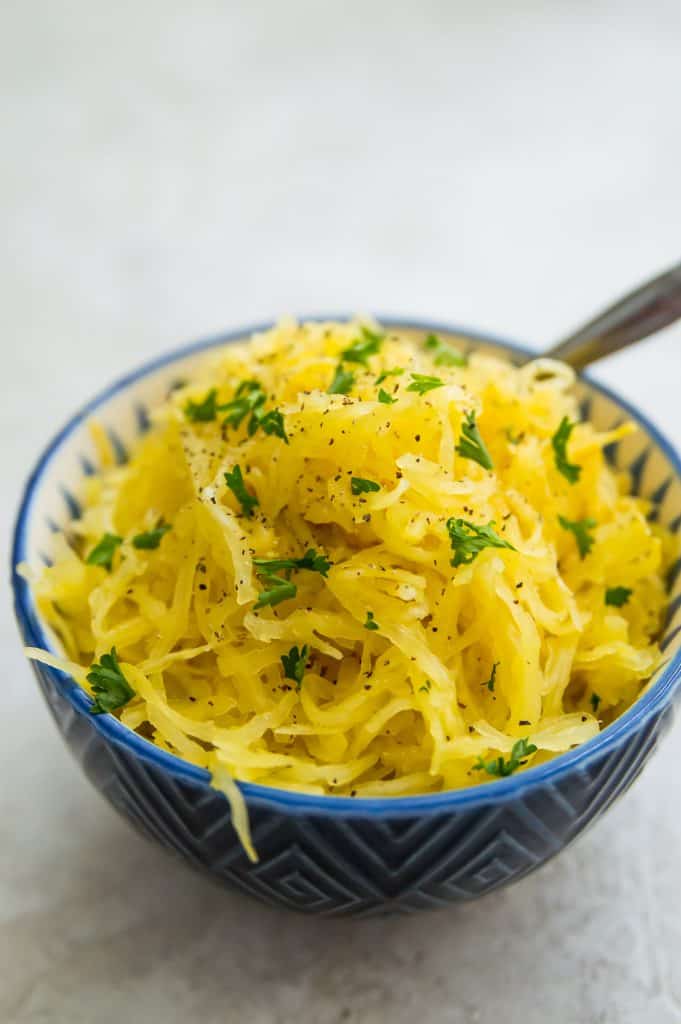 A bowl of air fryer spaghetti squash with pepper and parsley on top