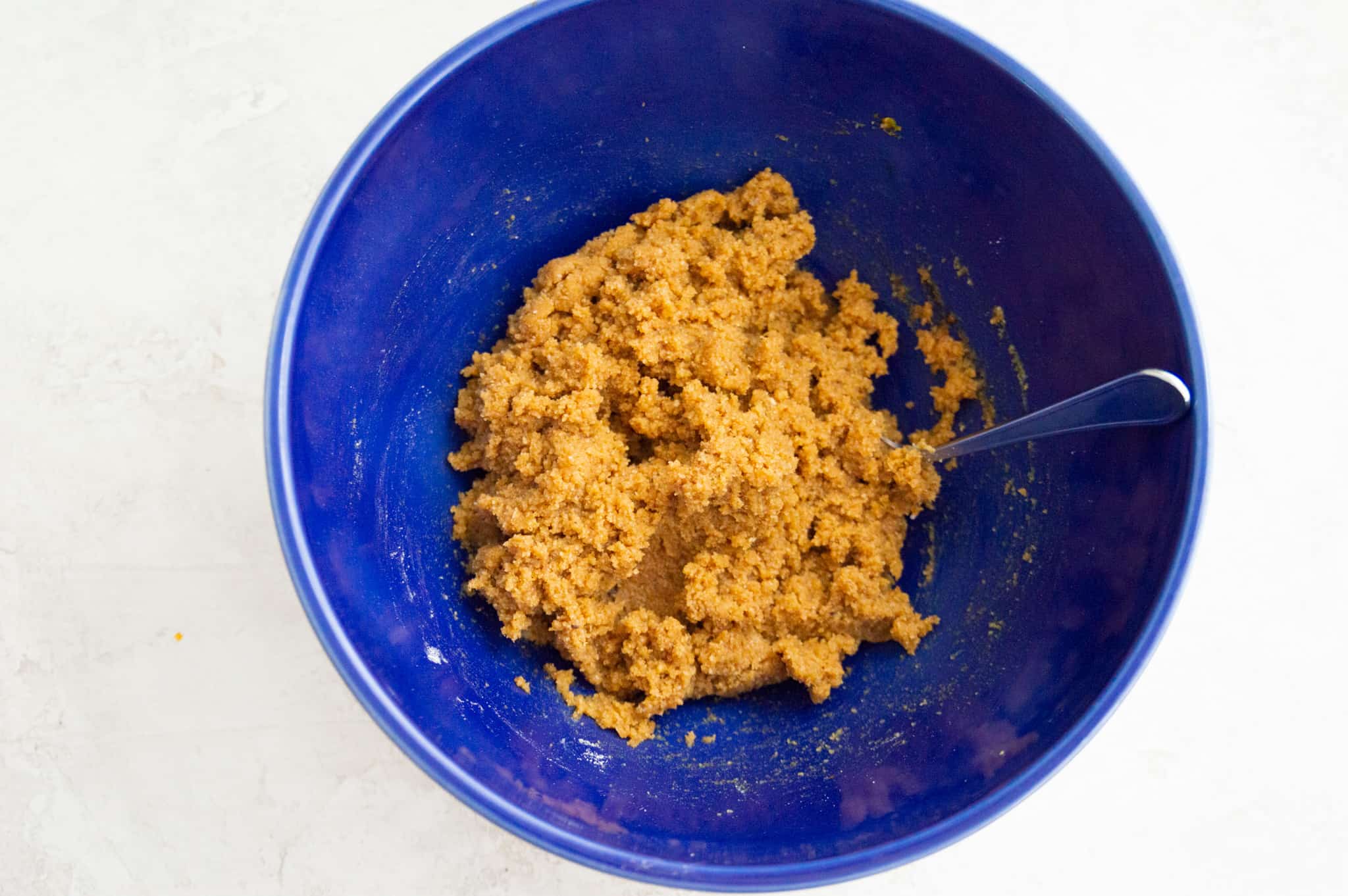 A blue bowl with cookie dough in it.