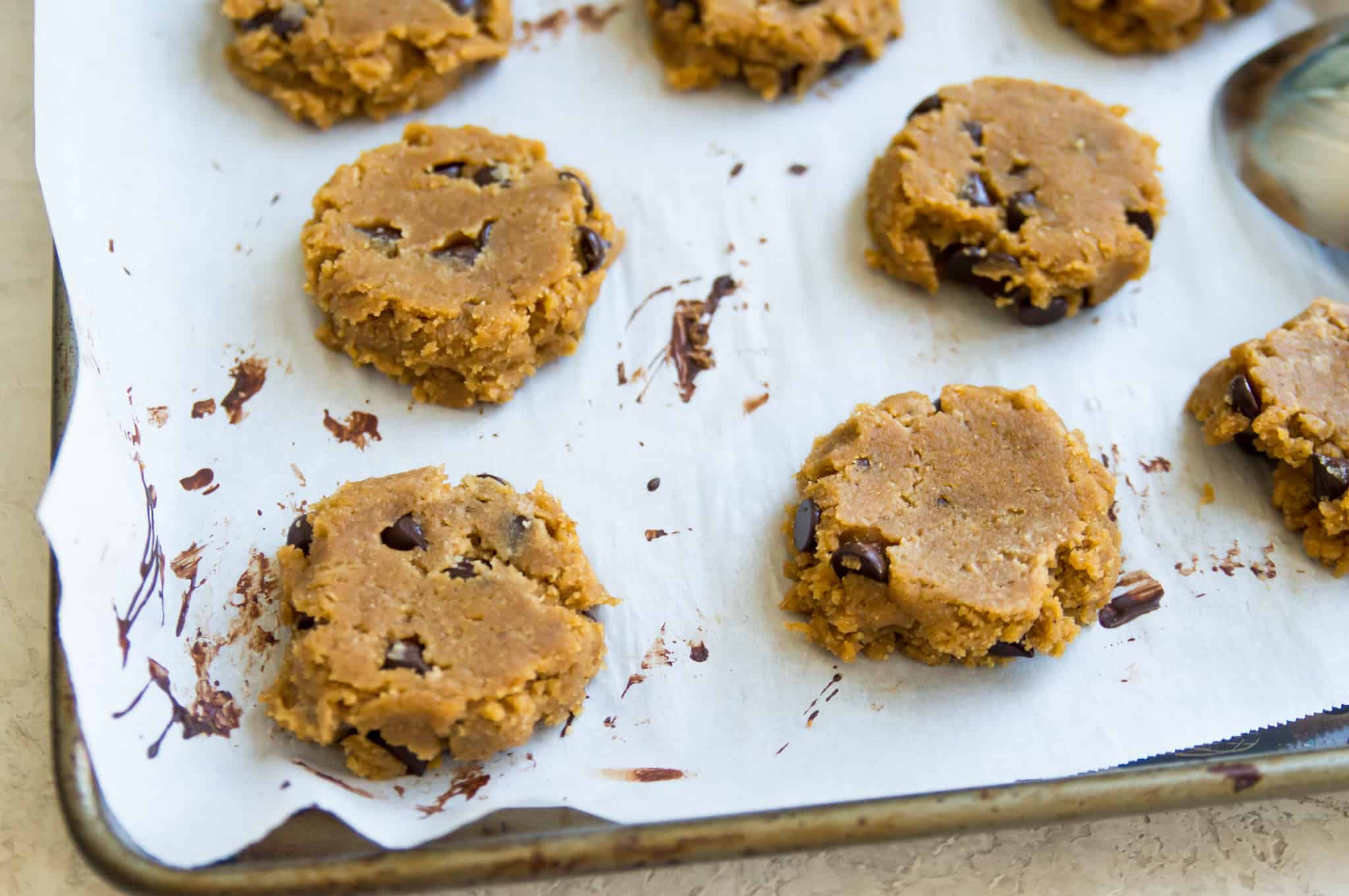 A baking sheet lined with parchment paper with raw cookie dough on it.