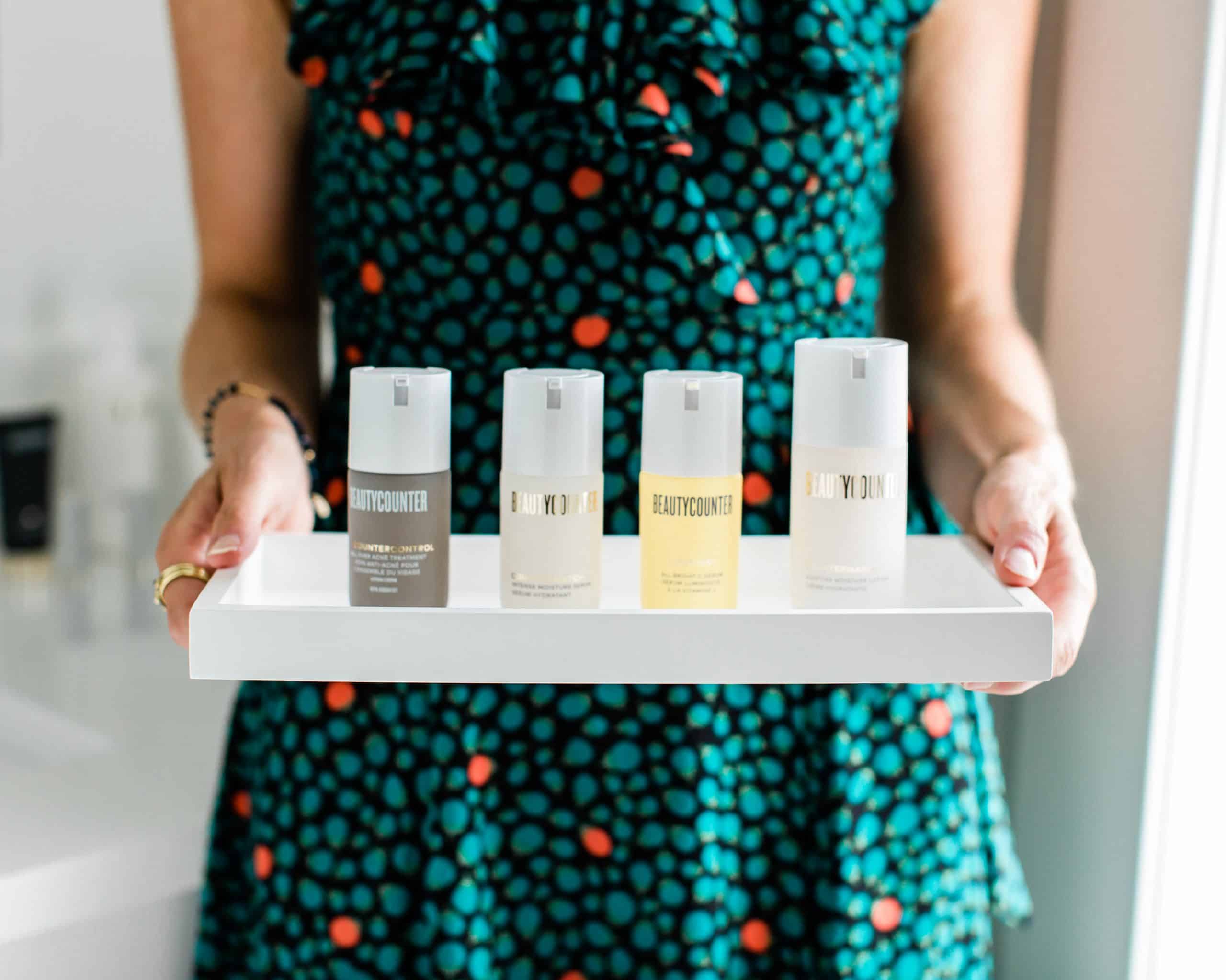 A girl holding a tray of Beautycounter skincare products that are used for acne.