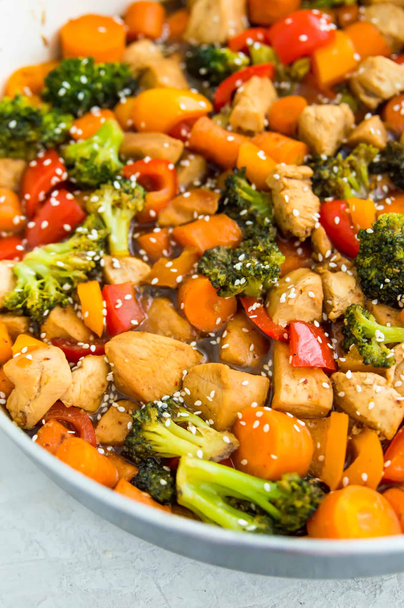 A pan filled with a Whole30 chicken stir fry covered in sauce and garnished with sesame seeds. 