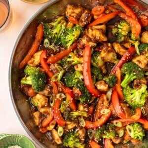 A pan filled with a chicken and vegetable stir fry with broccoli and chopped bell peppers.
