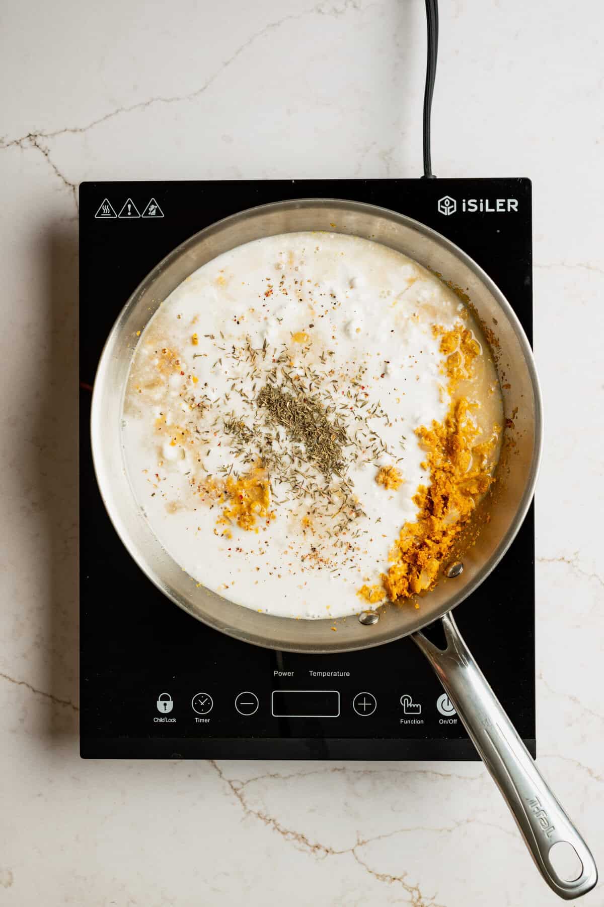 A pot with coconut milk, spices and nutritional yeast in it.