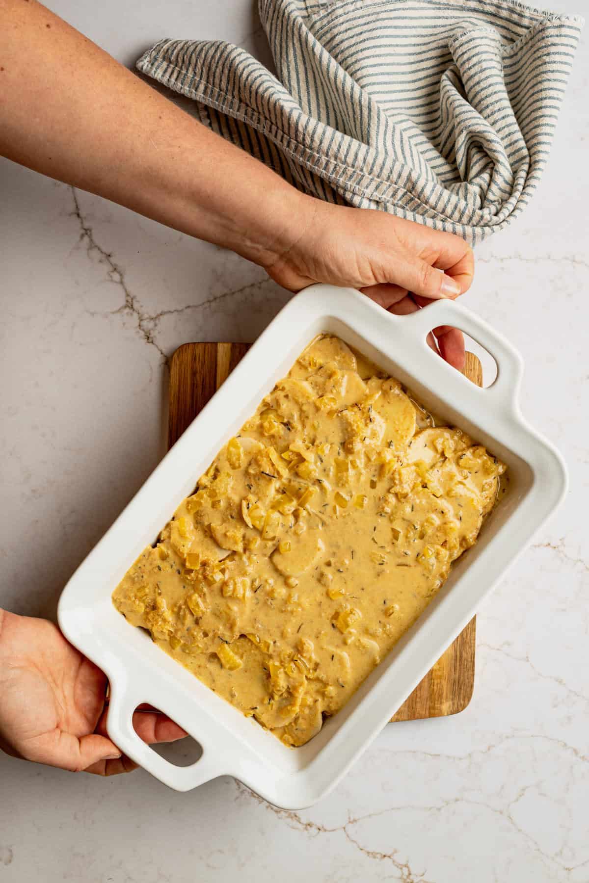 A casserole dish filled with uncooked scalloped potatoes. 
