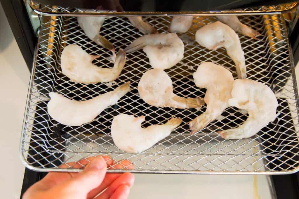 Frozen shrimp on an air fryer rack. 
