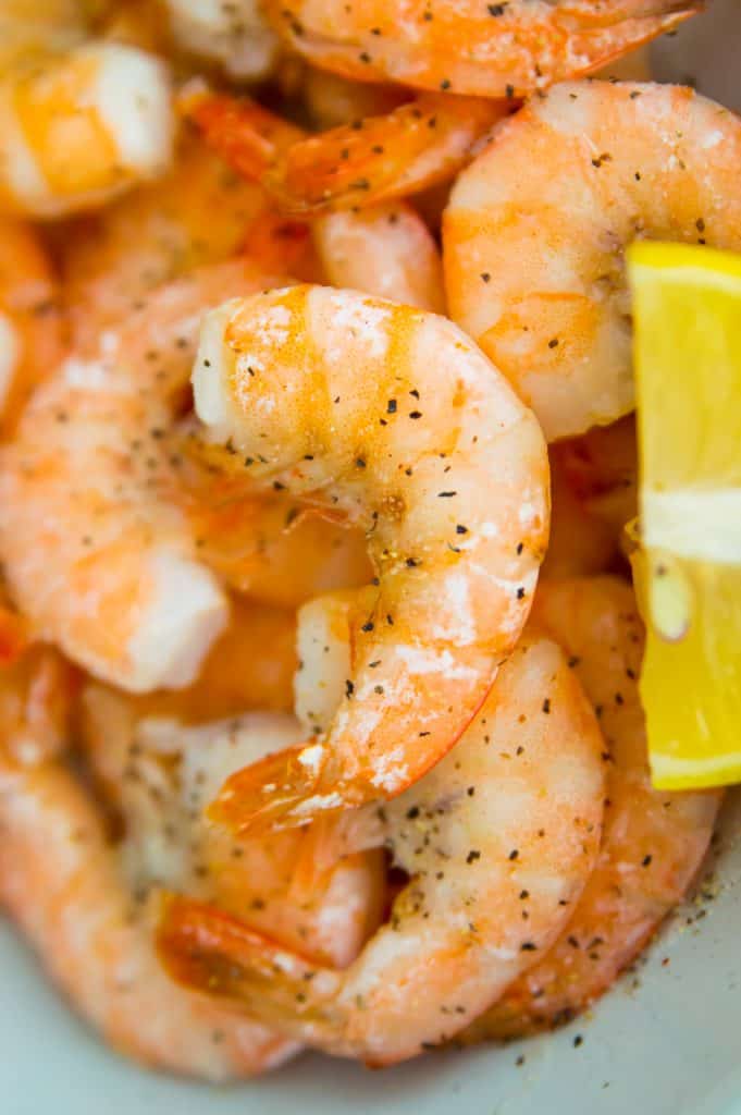 A close up photo of air fryer frozen shrimp in a bowl with lemon slices