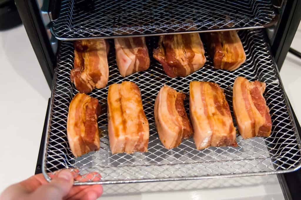 Marinated pork belly strips on an air fryer tray.