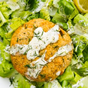 An air fryer salmon patties on a bed of chopped lettuce