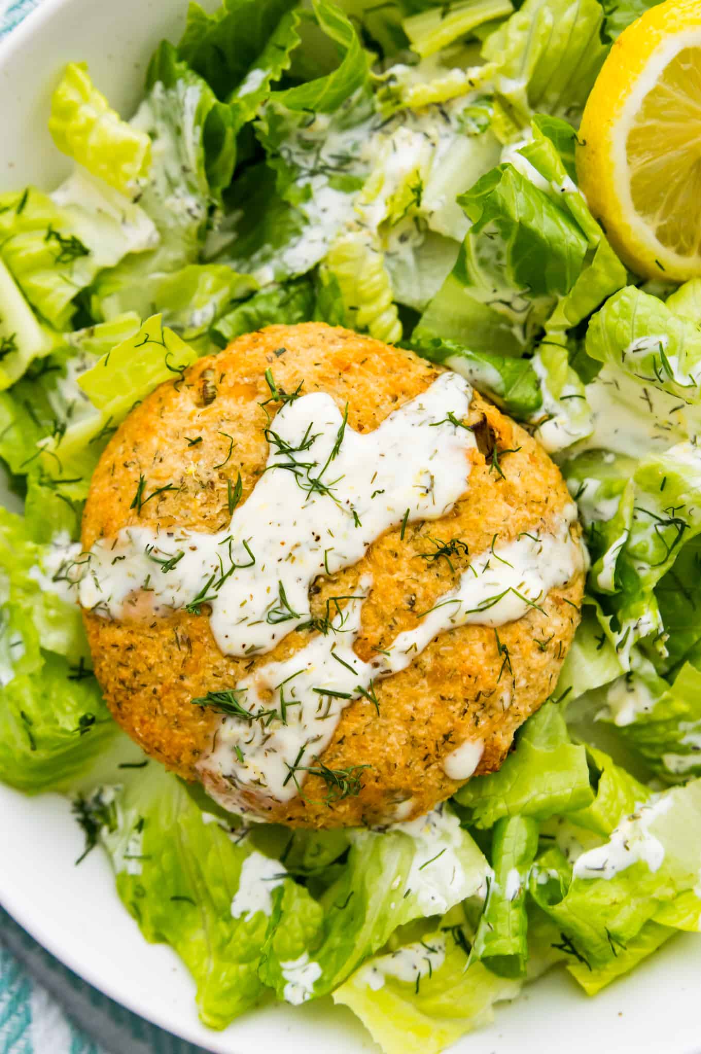 An air fryer salmon patties on a bed of chopped lettuce