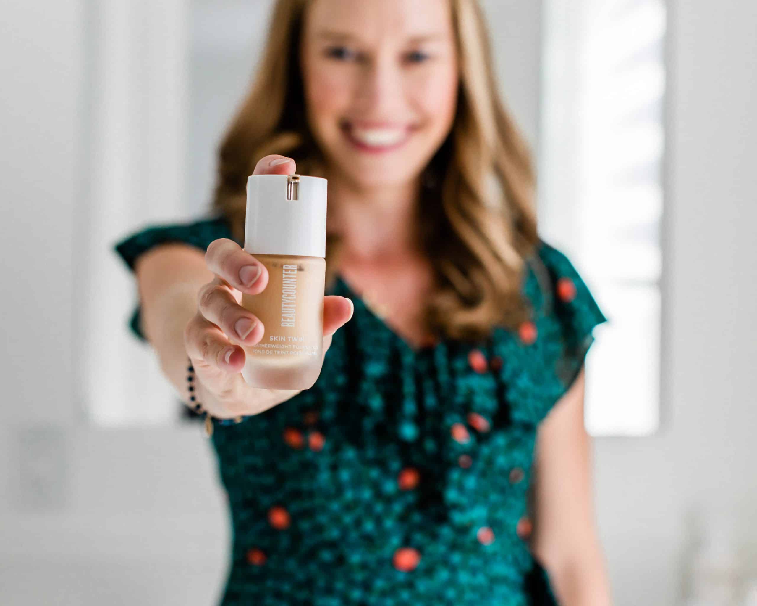 Erin Carter holding a bottle of Beautycounter foundation in front of her face.