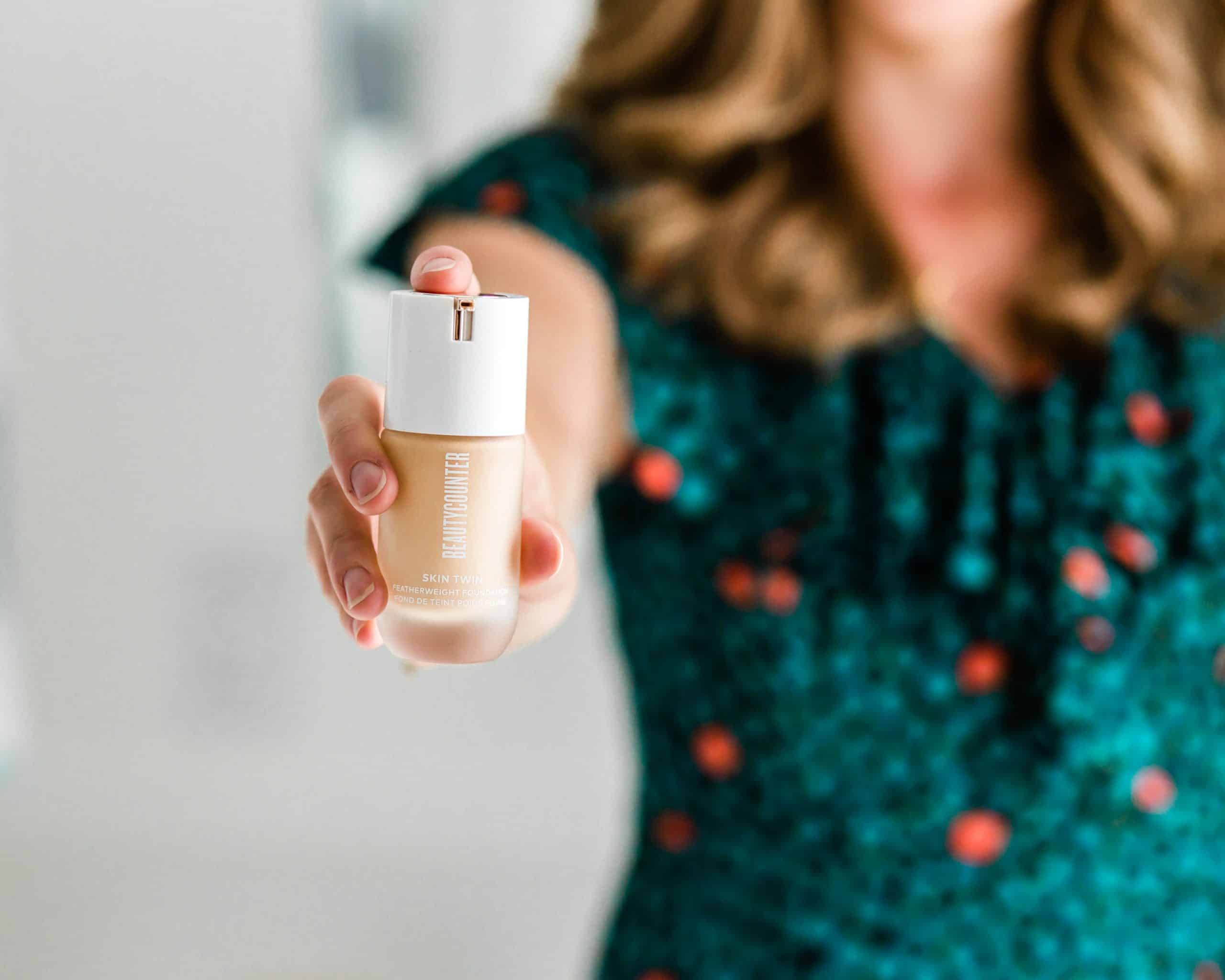 A girl holding a bottle of Beautycounter foundation.