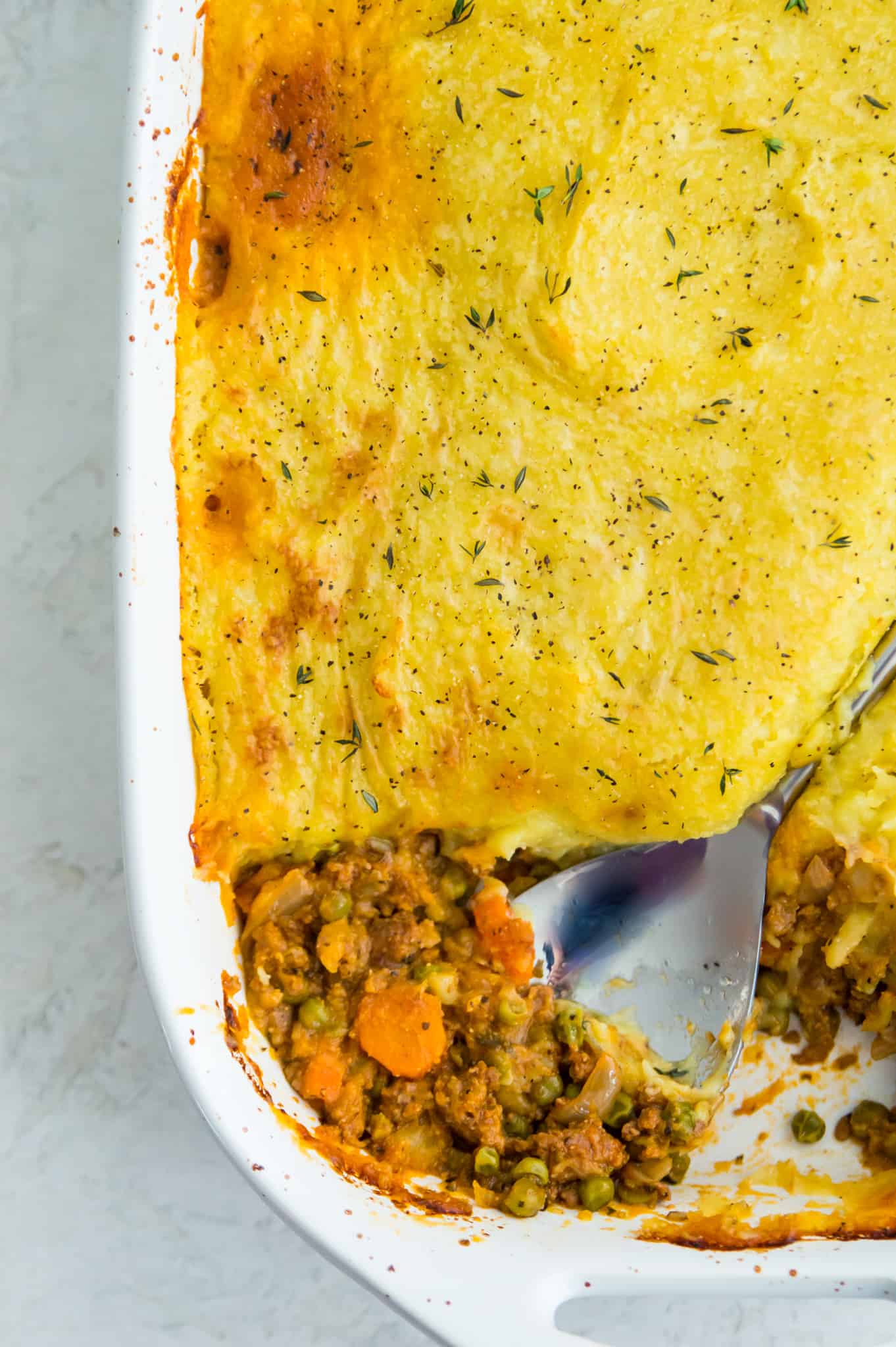 A casserole dish of Whole30 shepherd's pie with a serving spoon in it.