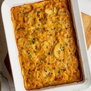 A pan filled with cooked dairy free scalloped potatoes garnished with fresh thyme.