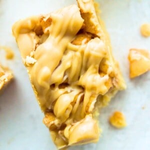 A paleo apple pie bar with a bite out of it and pieces of cooked apples beside it.