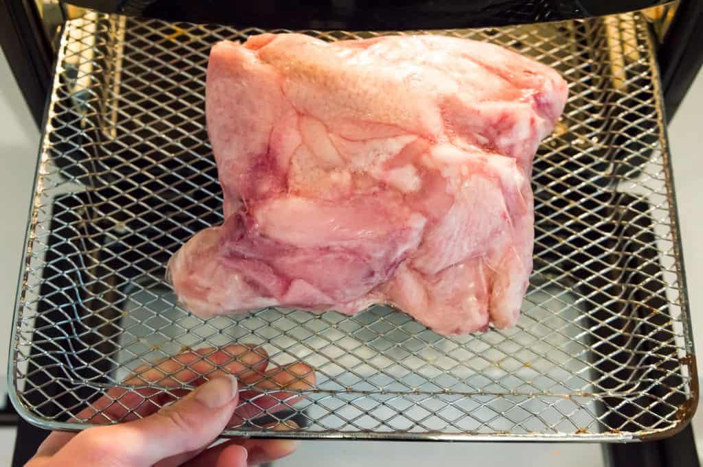 Frozen chicken wings on an air fryer rack. 