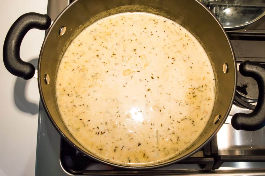 A pot on the stove with dairy free clam chowder cooking in it.
