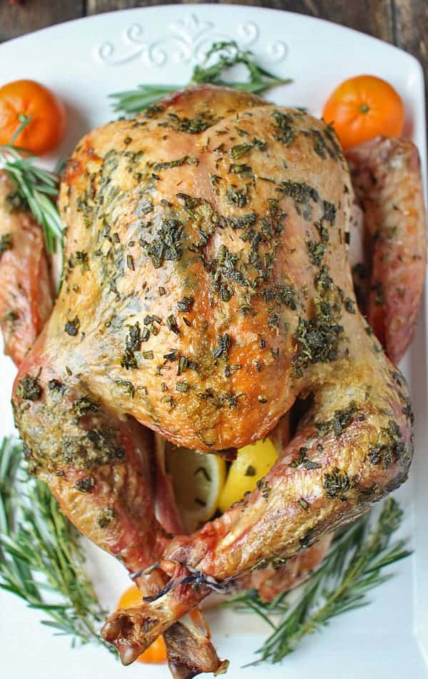 A platter with a whole paleo roasted turkey garnished with rosemary. 