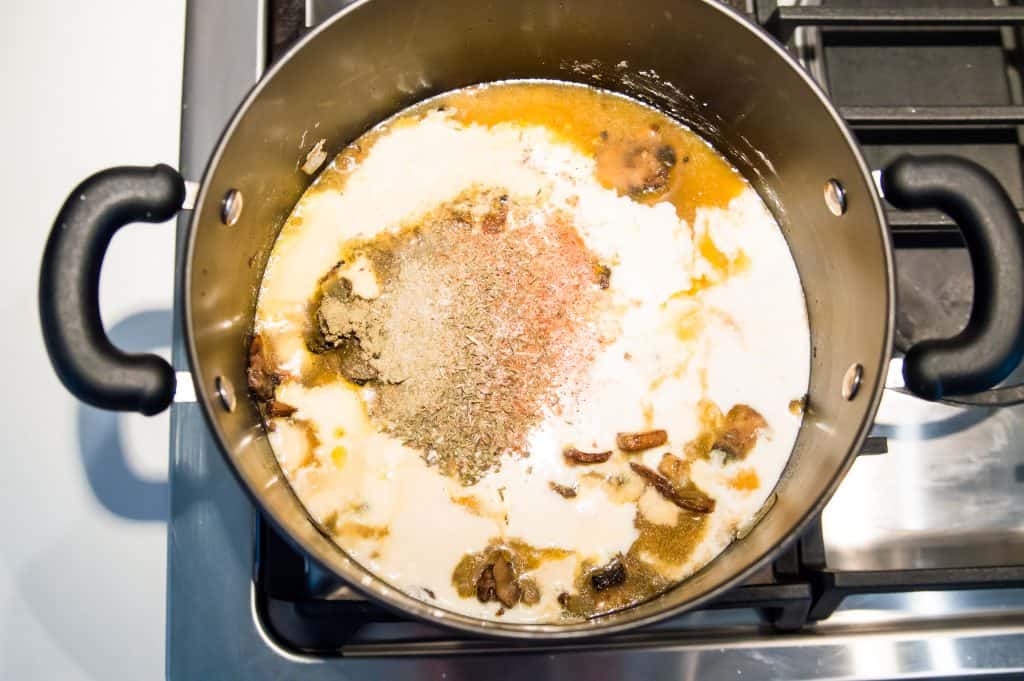 A large pot on the stovetop with the ingredients for making cream of mushroom soup in it.