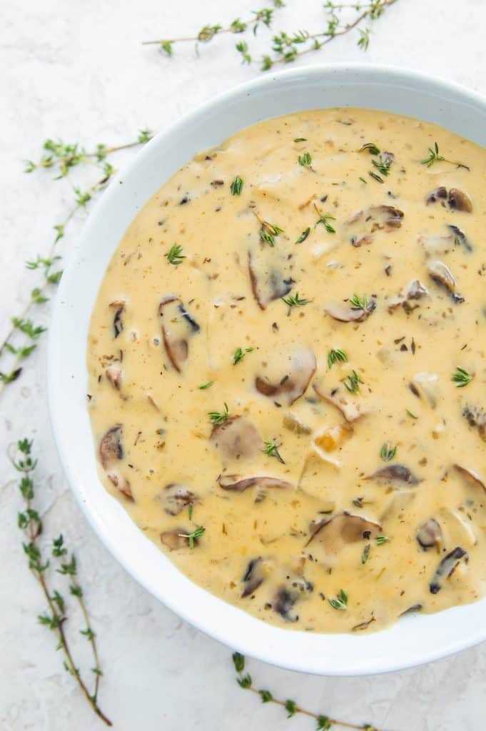 A large bowl of vegan cream of mushroom soup garnished with fresh thyme