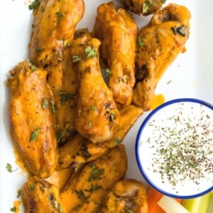 A plate of buffalo chicken wings with a side of ranch dressing.