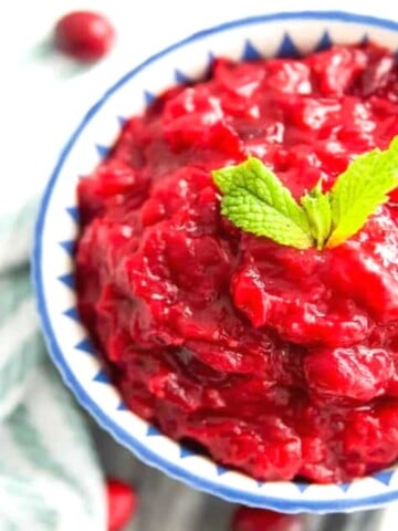 A bowl of sugar free cranberry sauce with mint leaves on top for garnish.