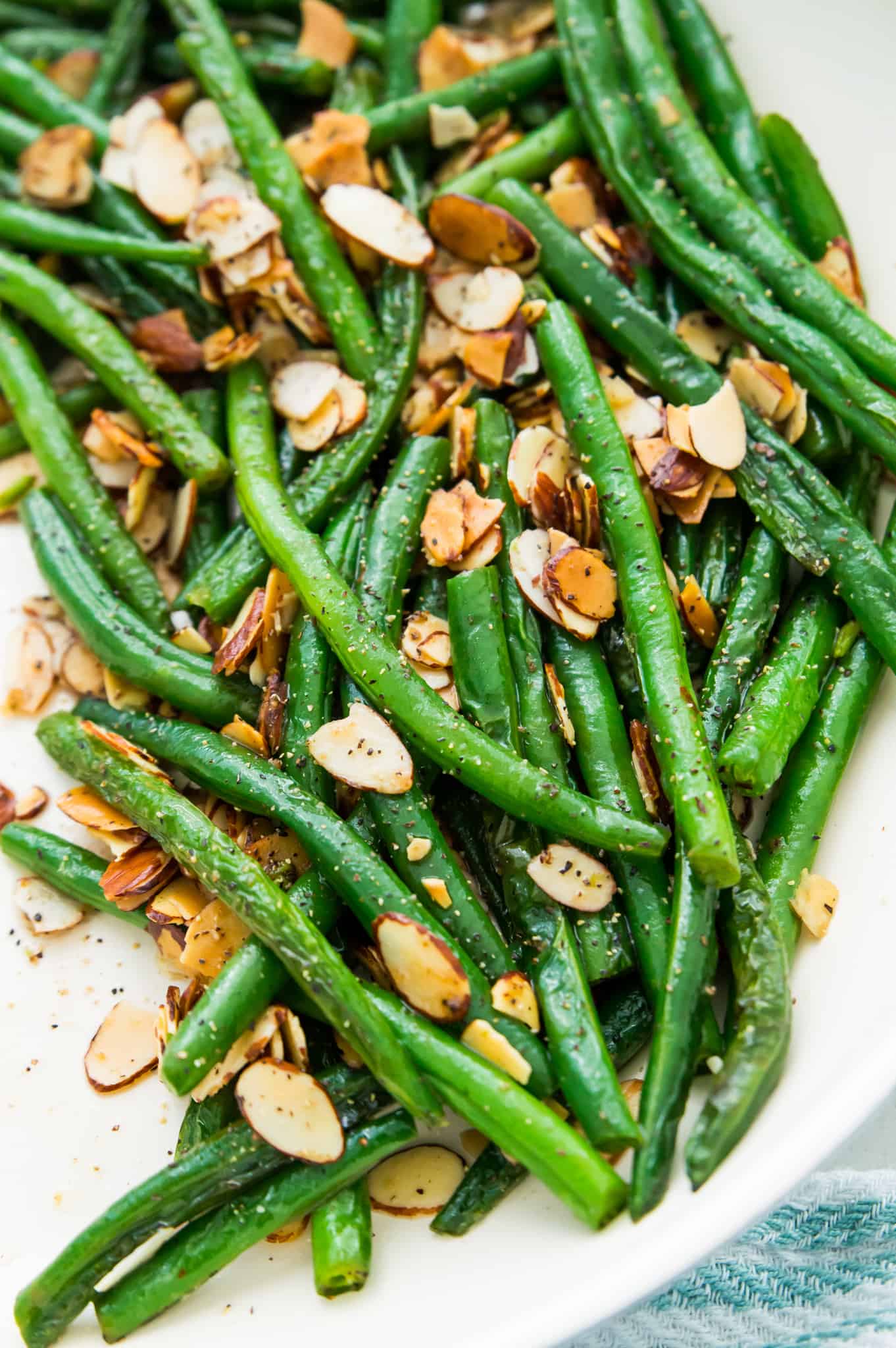 A dish filled with cooked green beans topped with slivered almonds.