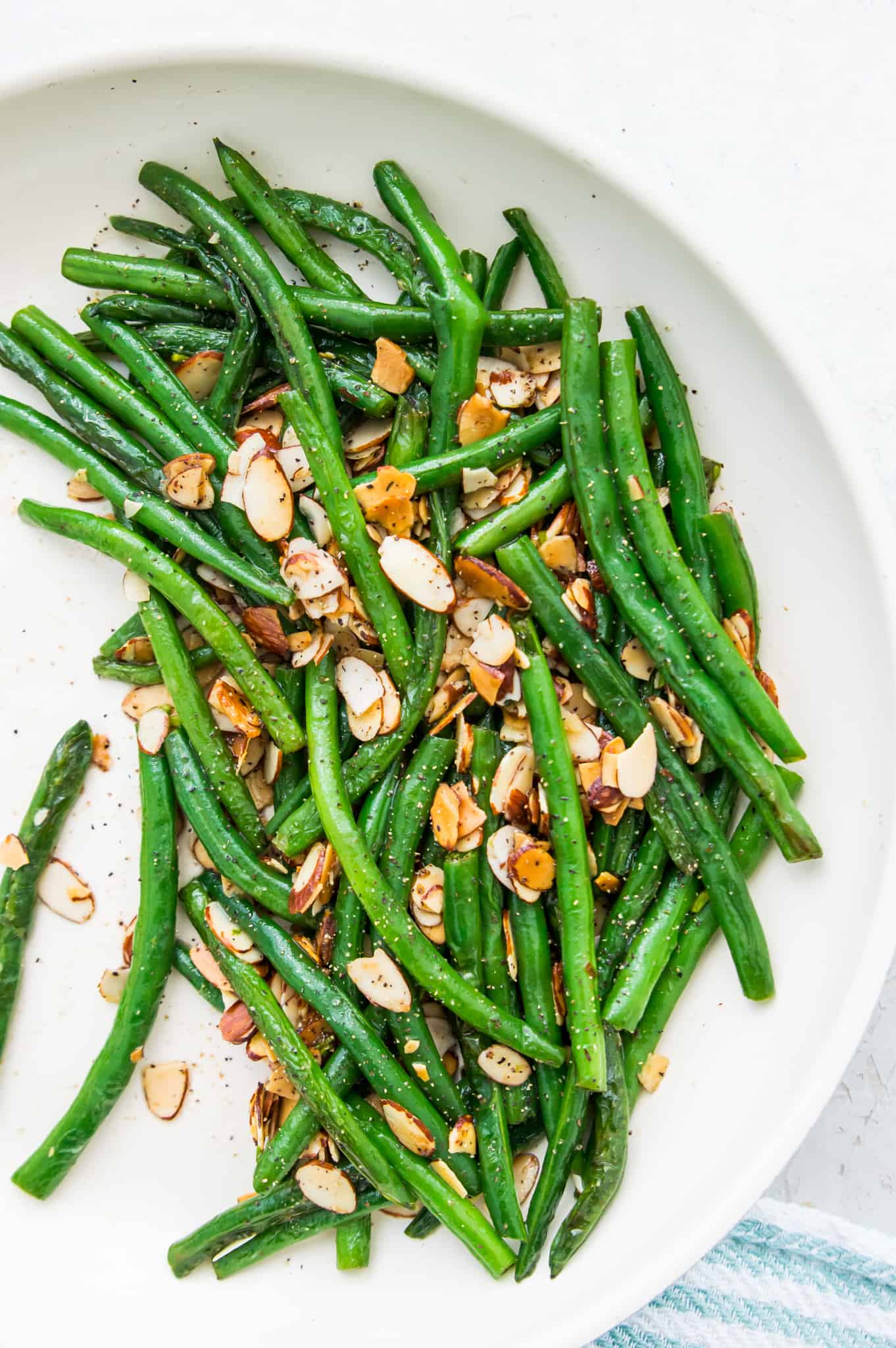 A pan full of cooked green beans topped with roasted slivered almonds. 