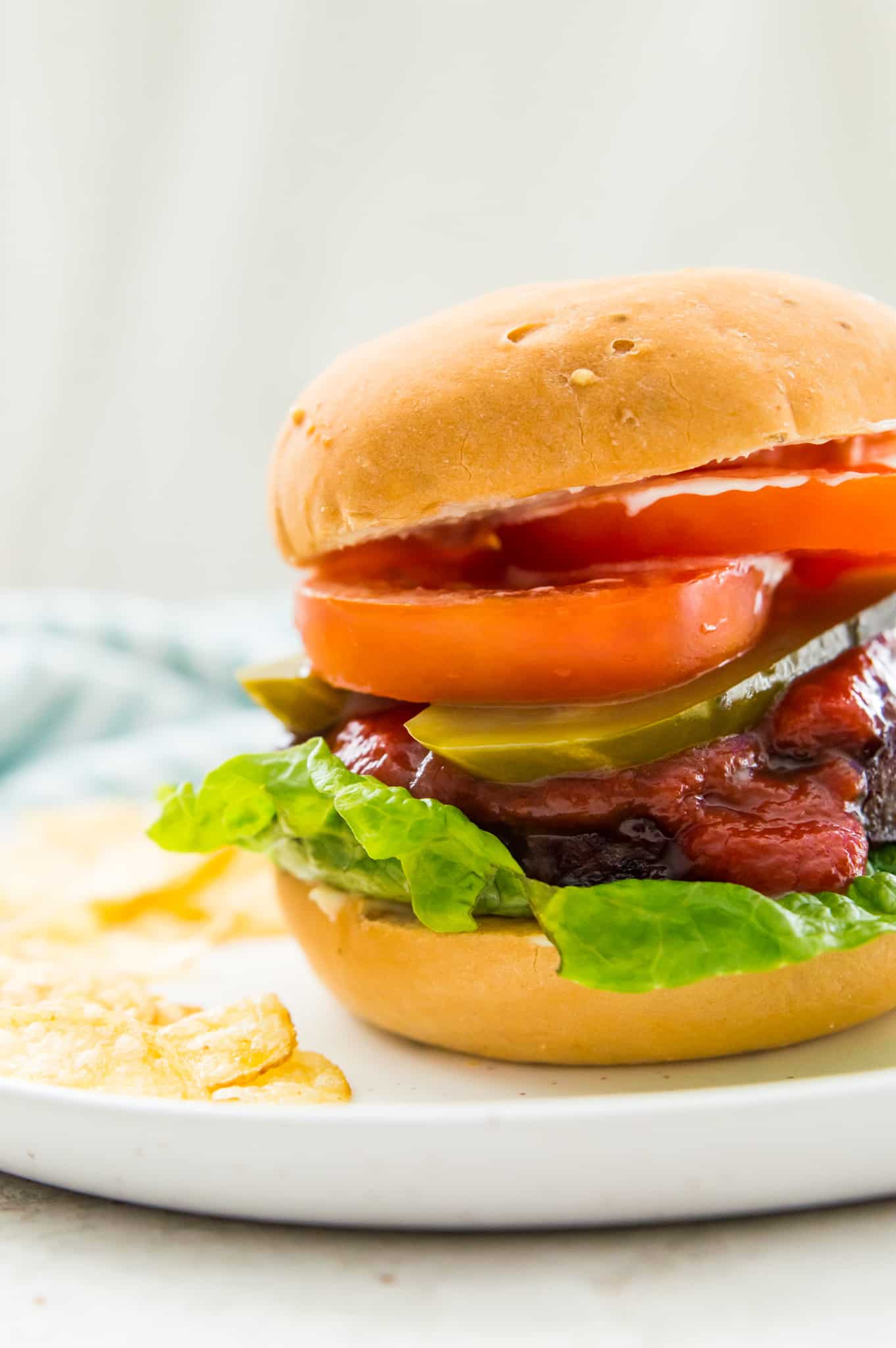 A hamburger in a bun with lettuce, sliced pickles and tomatoes. 