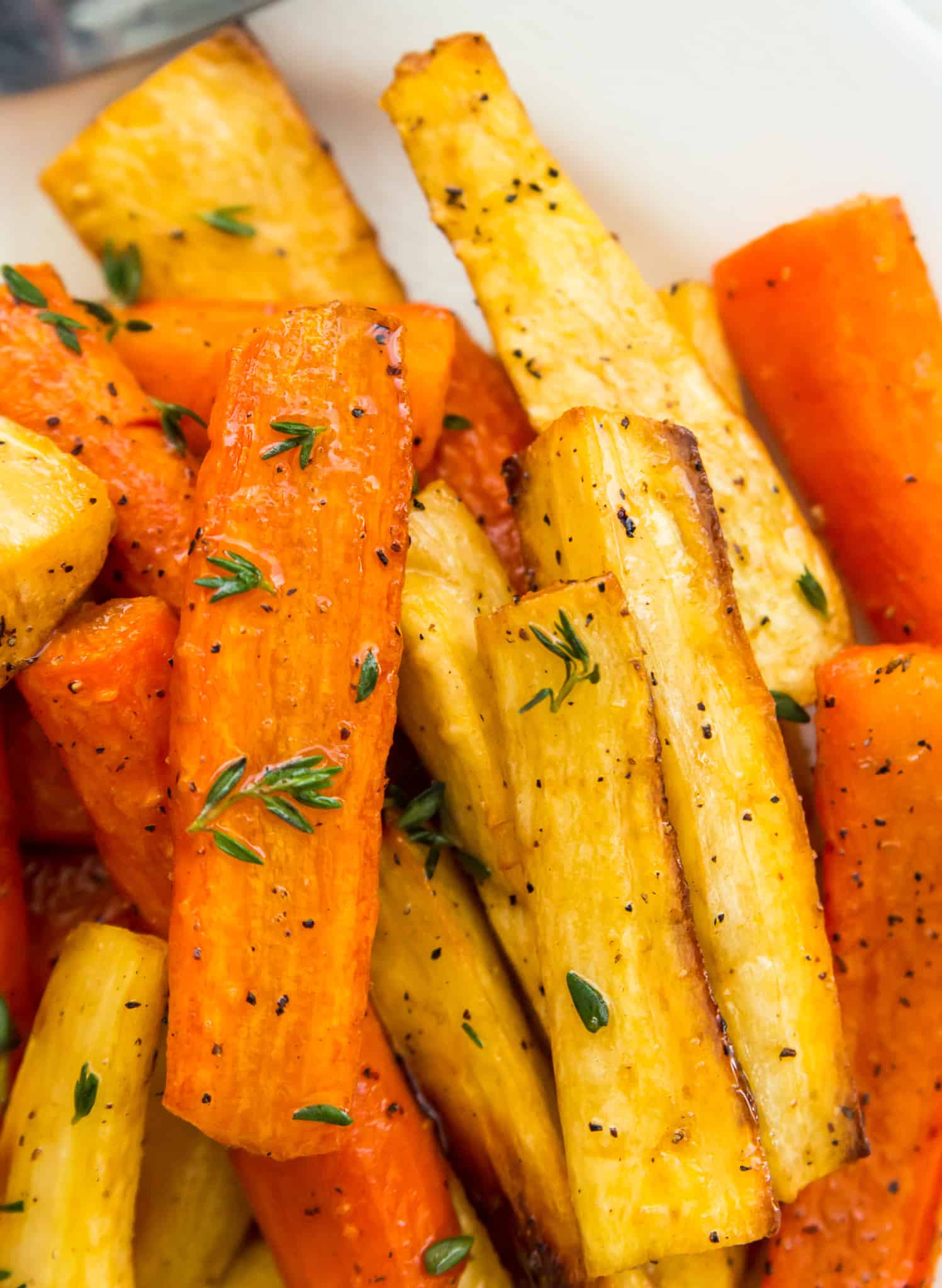 A bowl of honey glazed carrots and parsnips tipped with fresh thyme.