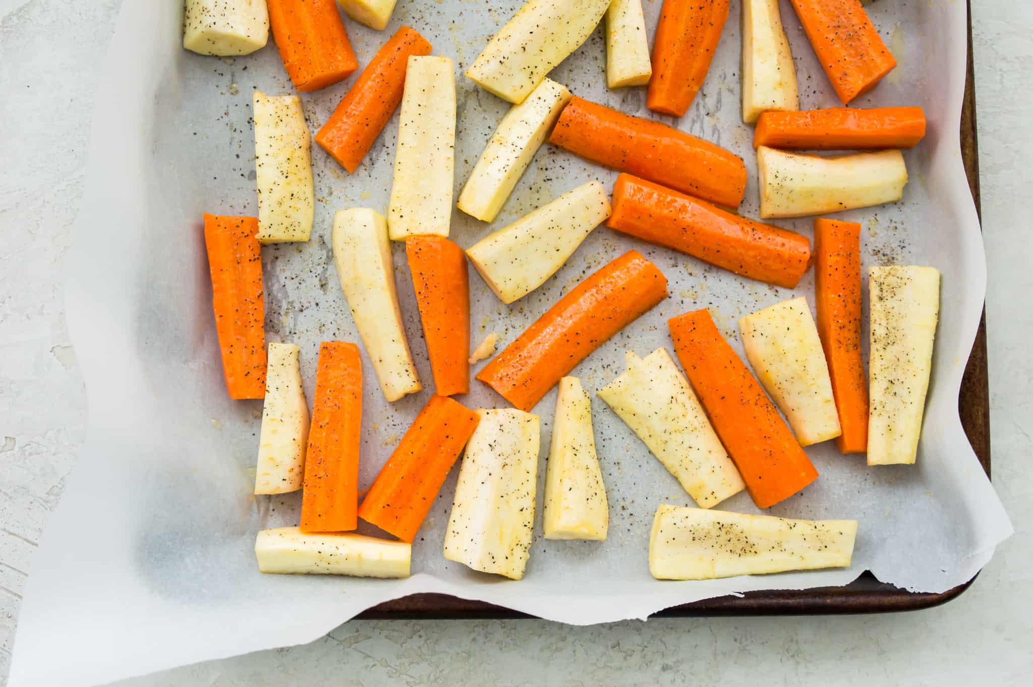 Chopped carrots and parsnips on a baking sheet.