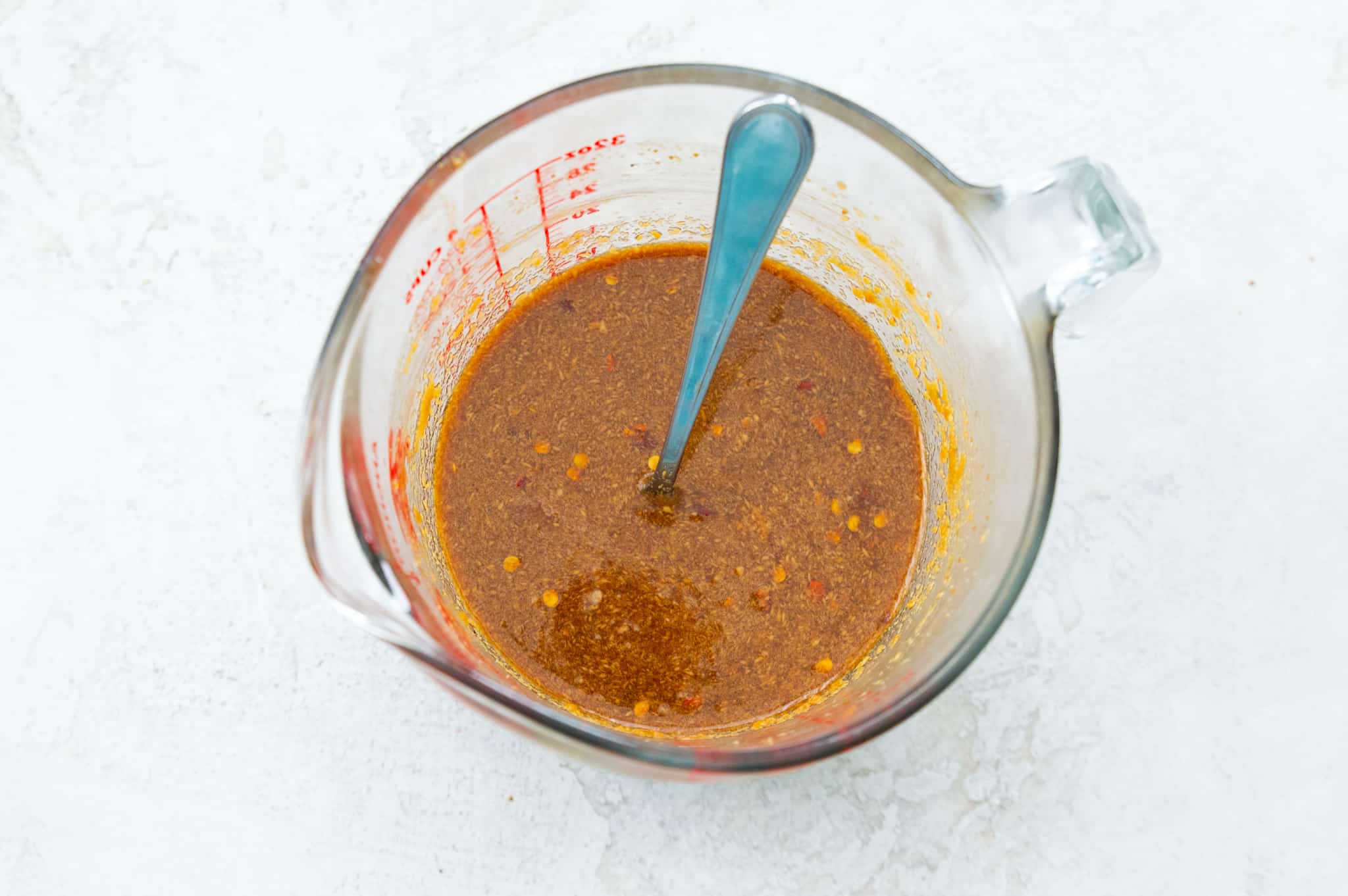 A glass measuring cup with a peanut sauce in it.